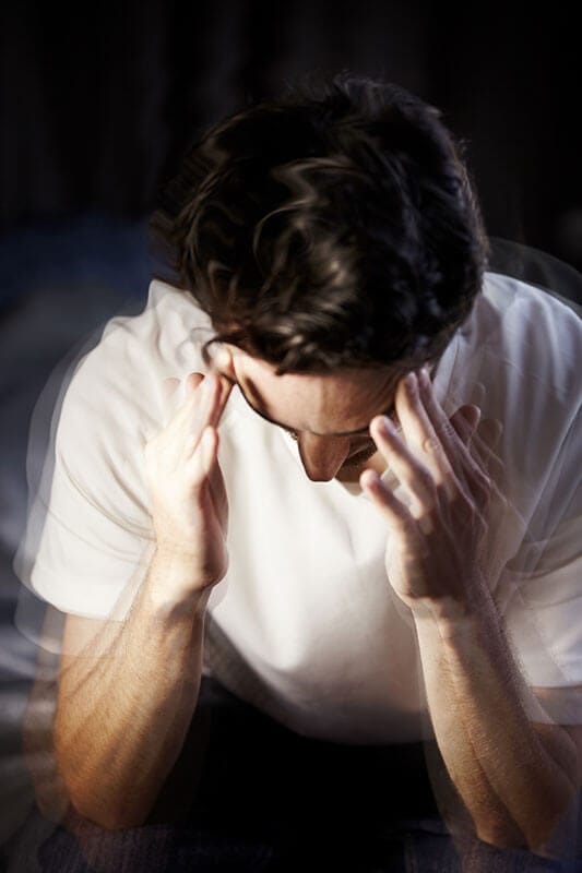 Man with hands on head, indicating a migraine